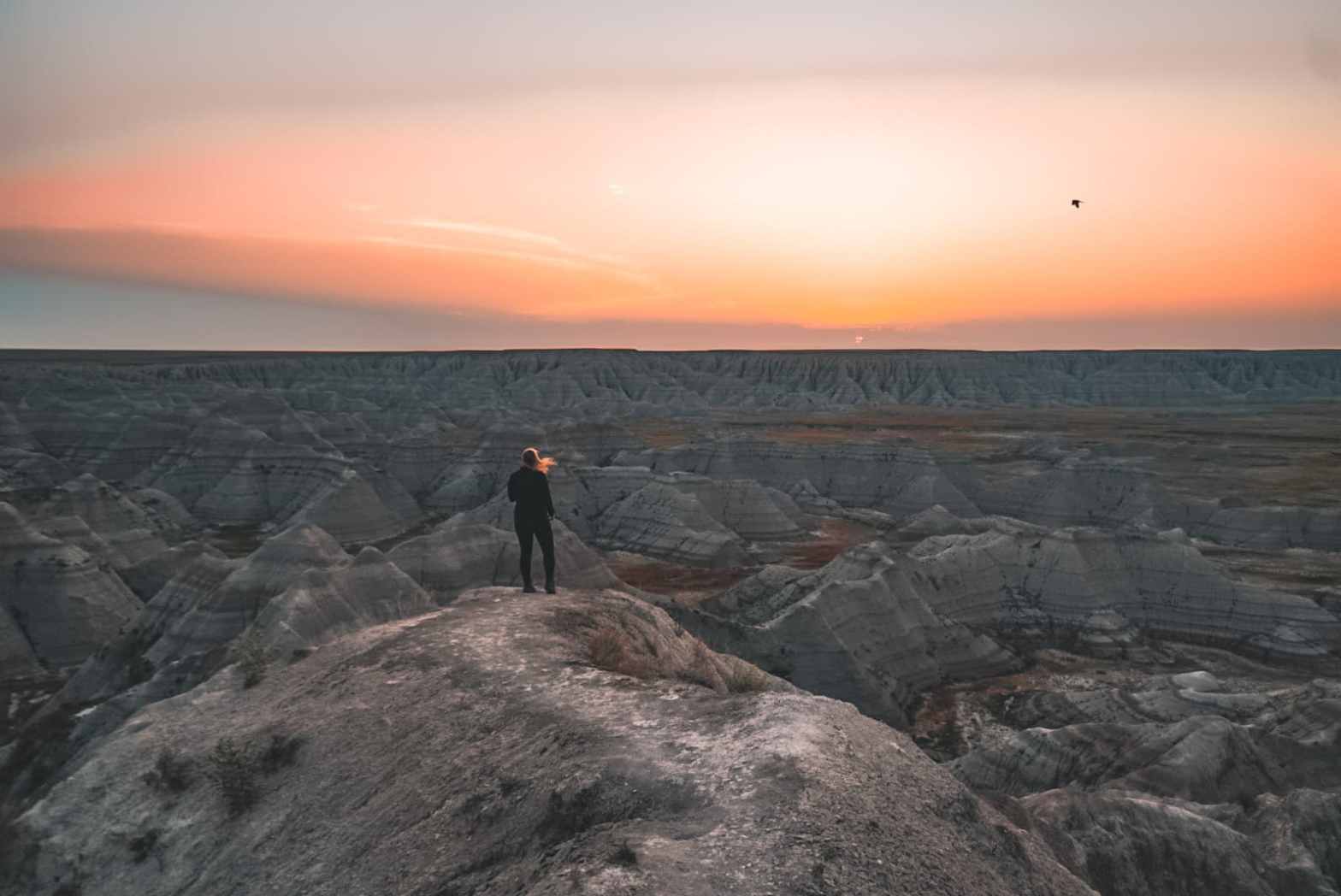 Woman standing near Badlands at sunrise 2