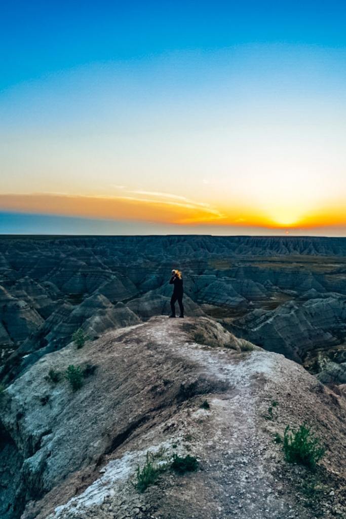 Woman standing near Badlands at sunrise, playing with hair