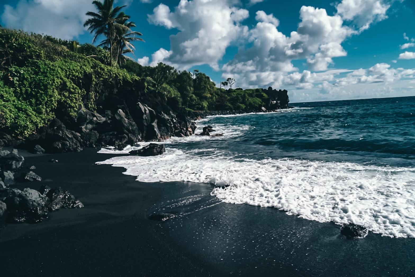 View from on the sand of a black sand beach out to the water