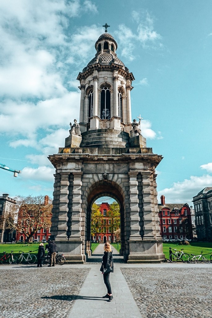 Woman standing in front of the college campus for Trinity College in Dublin