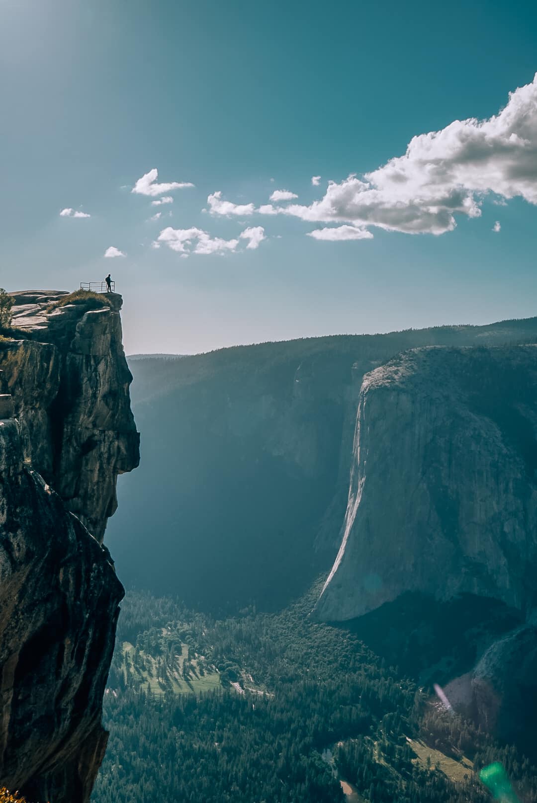 Woman standing far away at the top of Taft Point with Yosemite Valley in the background