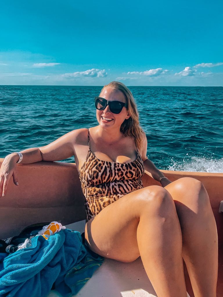 Woman wearing a leopard print one piece swimsuit sitting on a boat