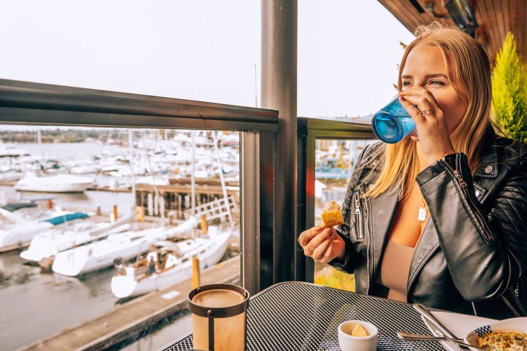 Woman taking a drink of water at a window seat at Duke's Seafood in Seattle