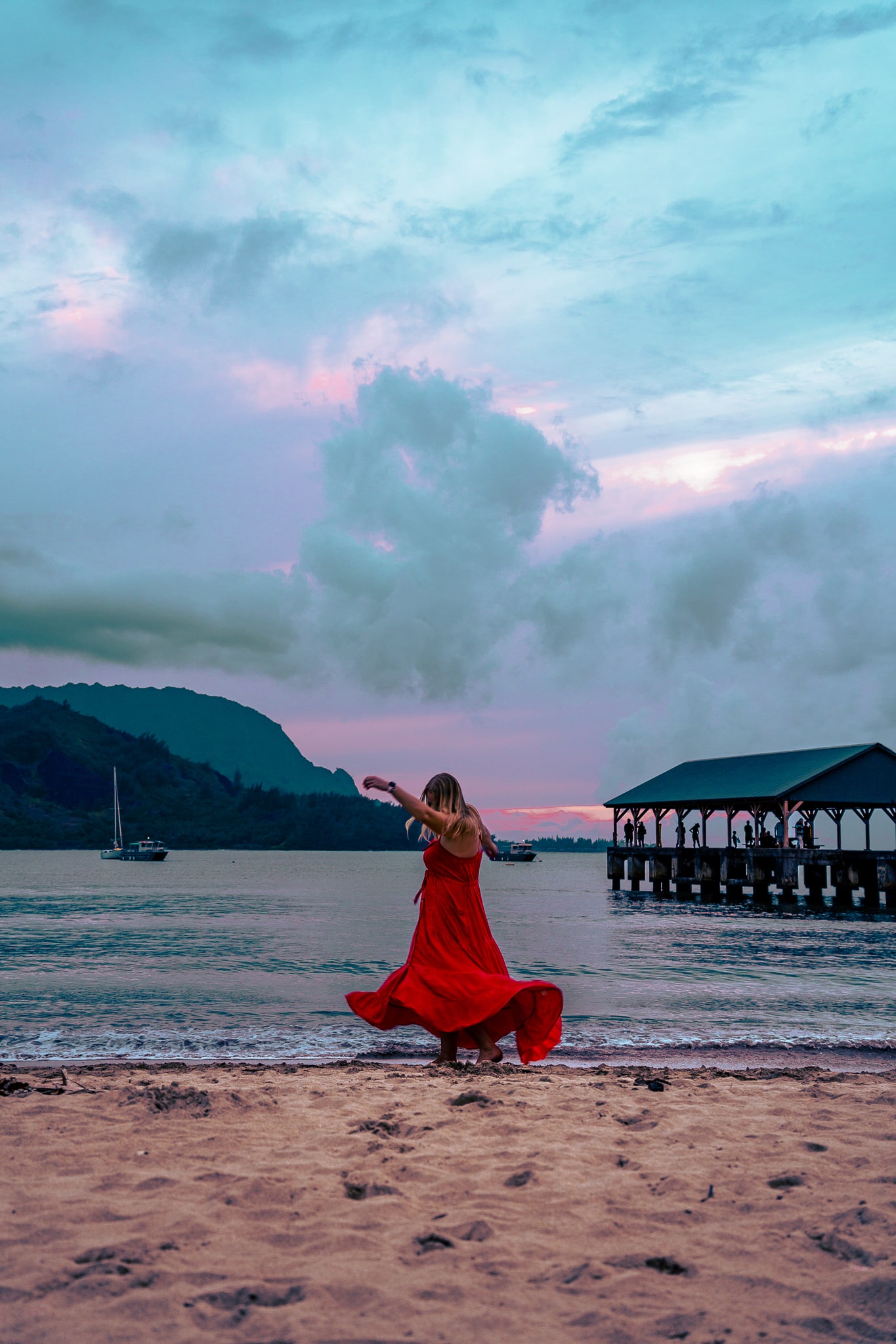 Woman spinning on the beach with her dress flowing at sunset at Hanalei Bay