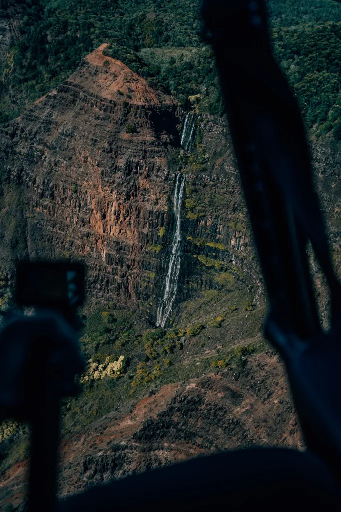 View of a waterfall in Waimea Canyon from inside a helicopter