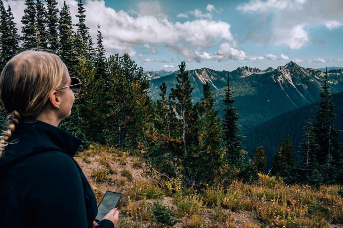 Woman holding phone, looking out to the mountains at Mount Rainier National Park