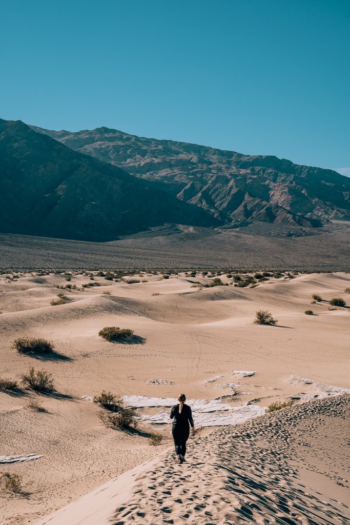 Woman walking along the ridge toward the mountains in the Mesquite Flat Sand Dunes at Death Valley National Park