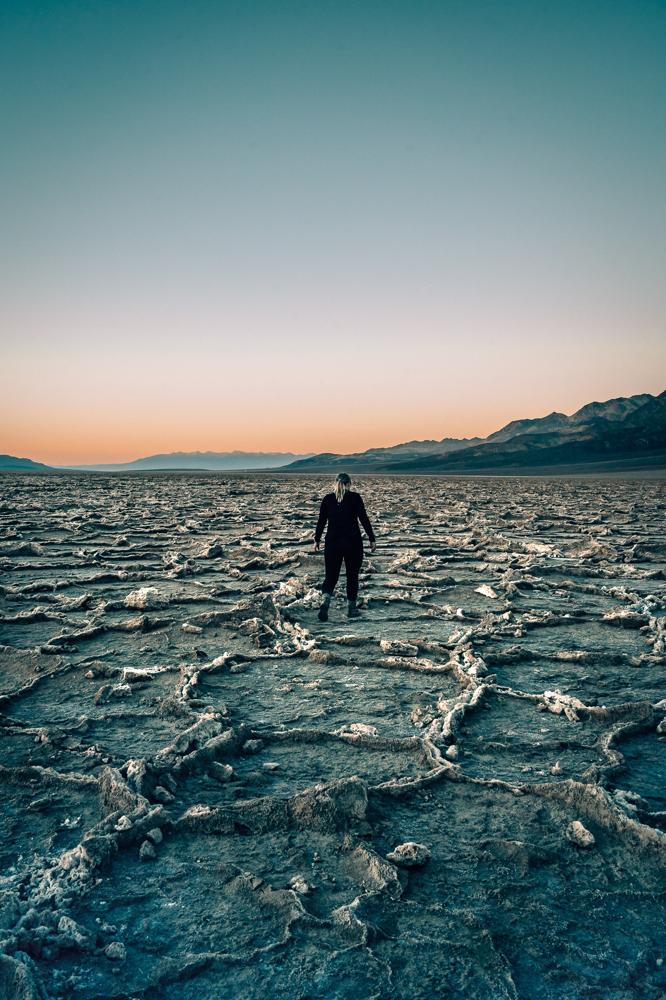 Woman walking along the salt flats of Badwater Basin at sunset in Death Valley National Park