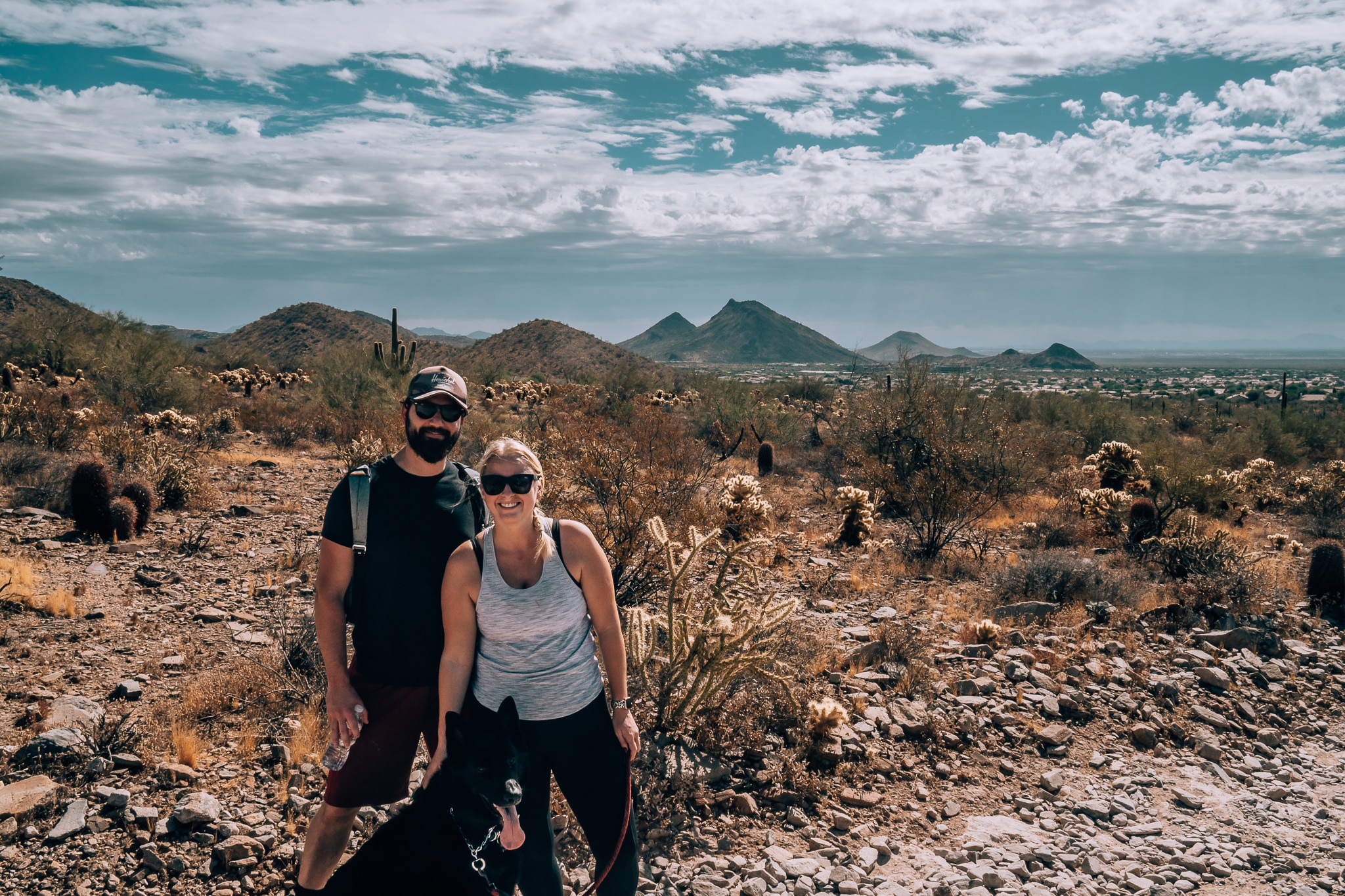Man, woman, and their black German Shepherd hiking in Arizona