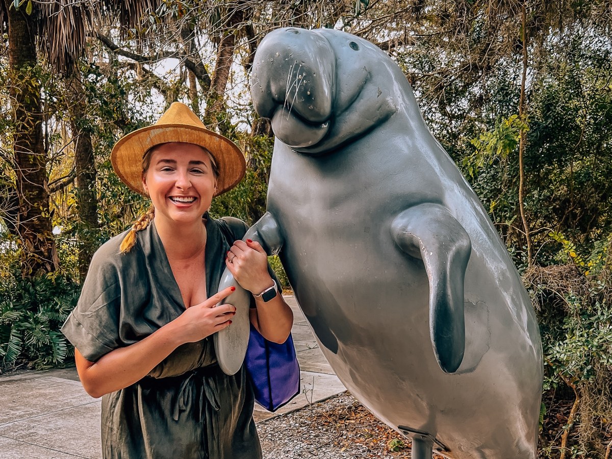 Woman standing next to a statue of a manatee at Manatee Park in Fort Myers