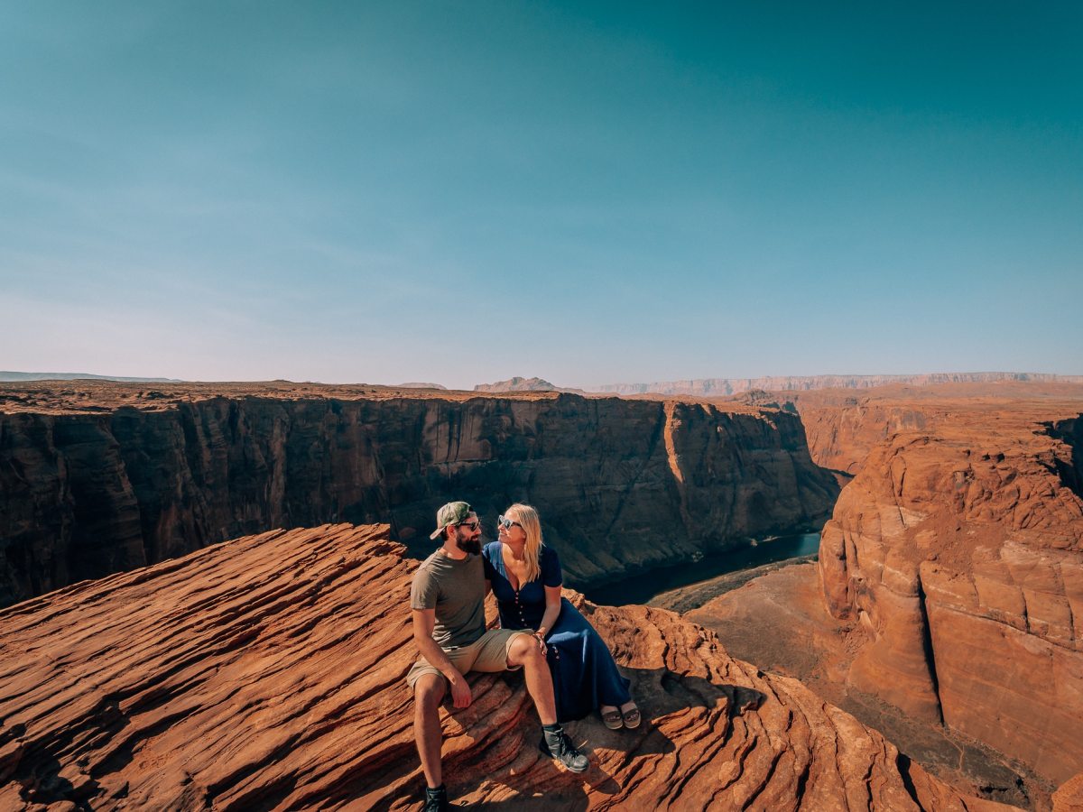 Man and woman couple sitting along the edge at Horseshoe Bend in Page, Arizona