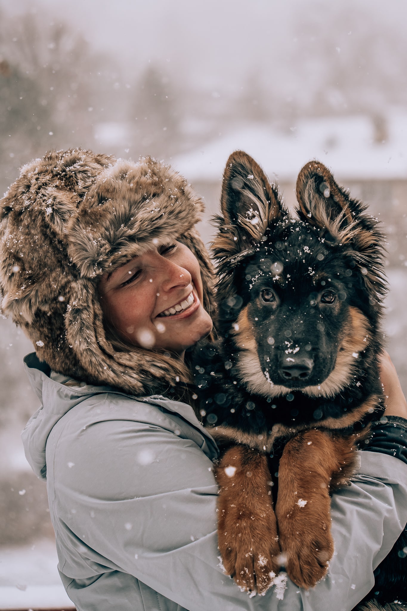 Woman holding her German Shepherd puppy while it snows out