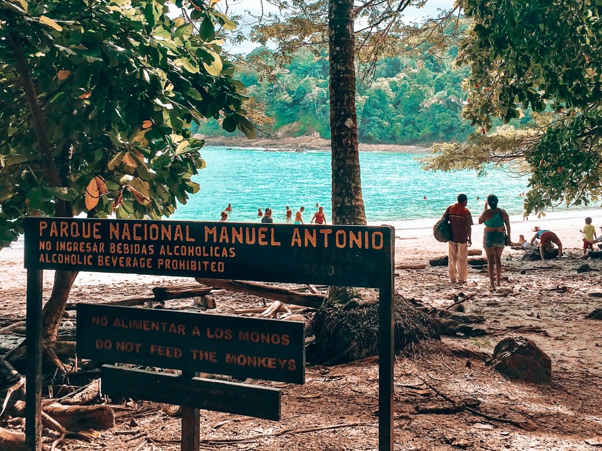 Shot of the sign for Manuel Antonio National Park with the beach in the background