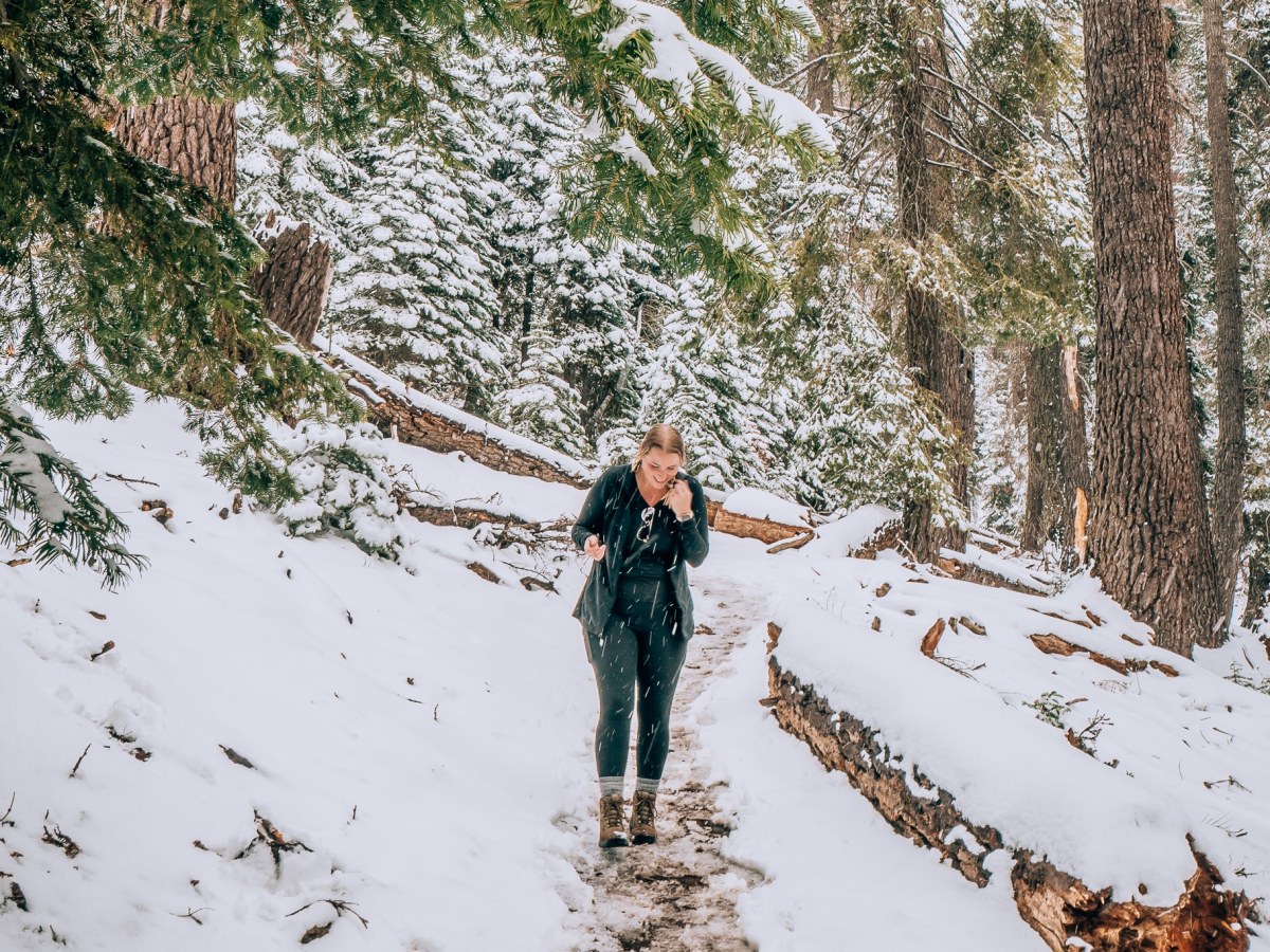 Woman walking through a very snowy trail in Sequoia National park