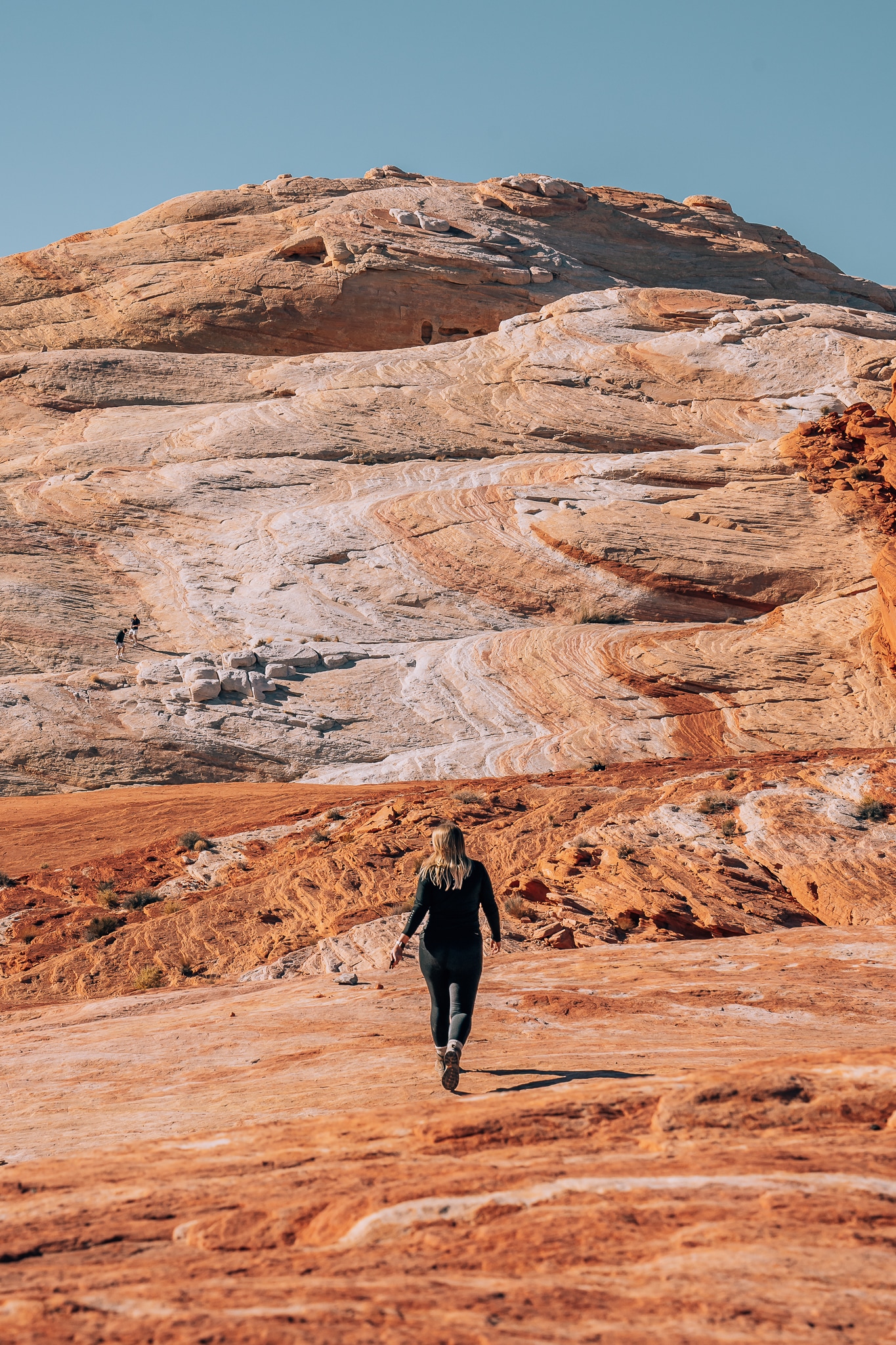 Woman walking on red rocks out up onto a hill of red rocks