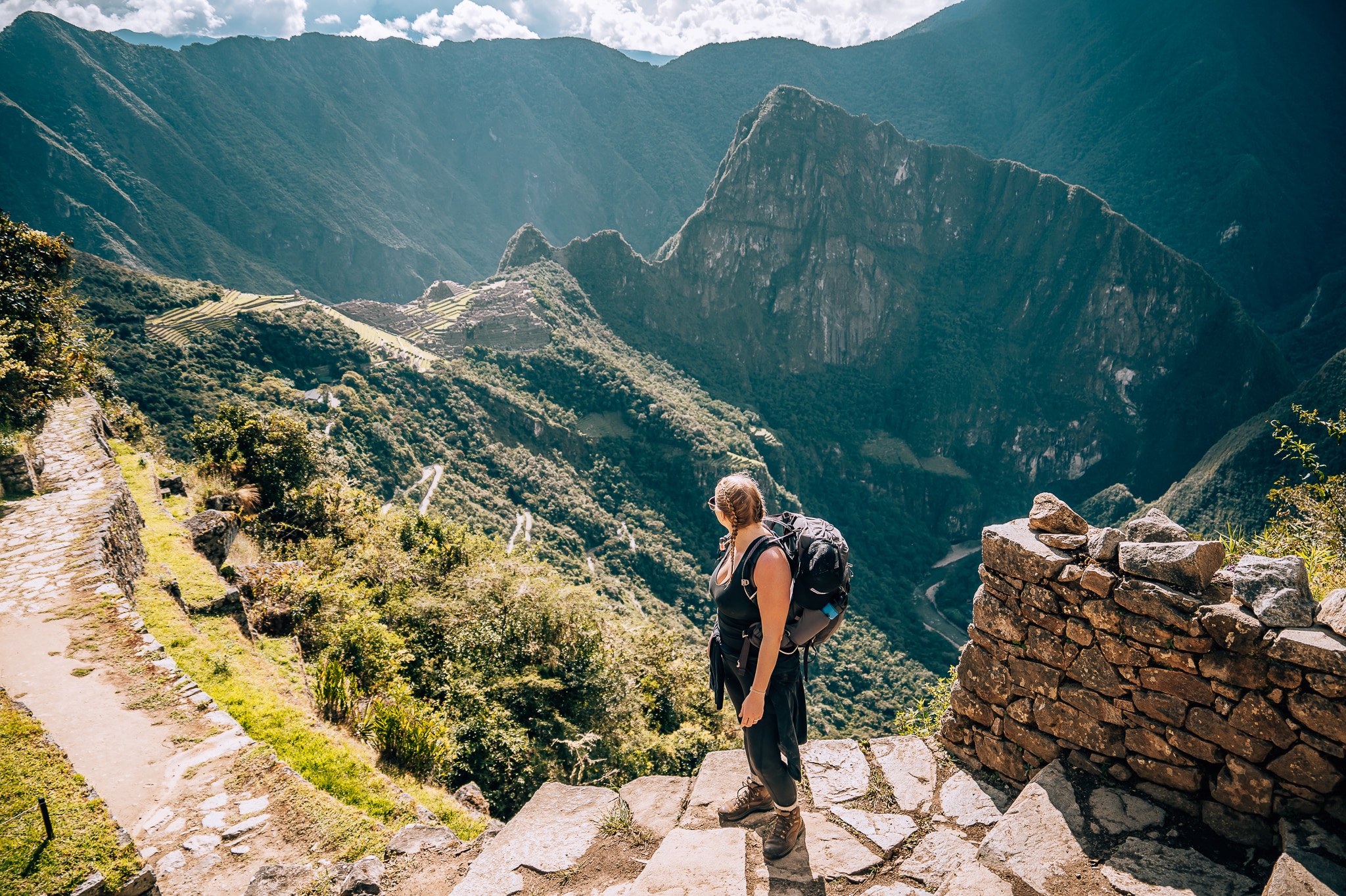 Woman standing up at the sun gate of the Inca Trail looking over to the Machu Picchu citadel