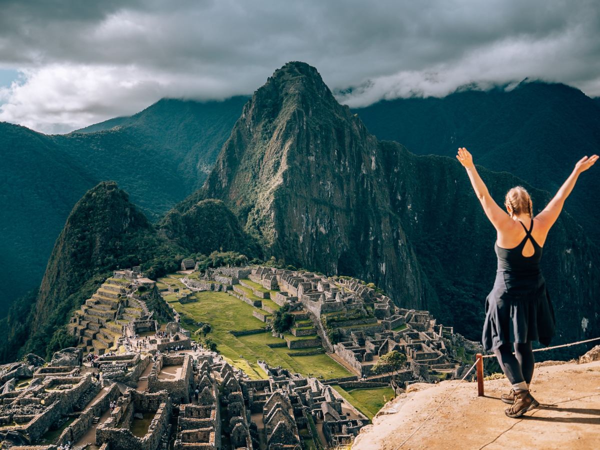Woman standing with her arms raised in front of Machu Picchu