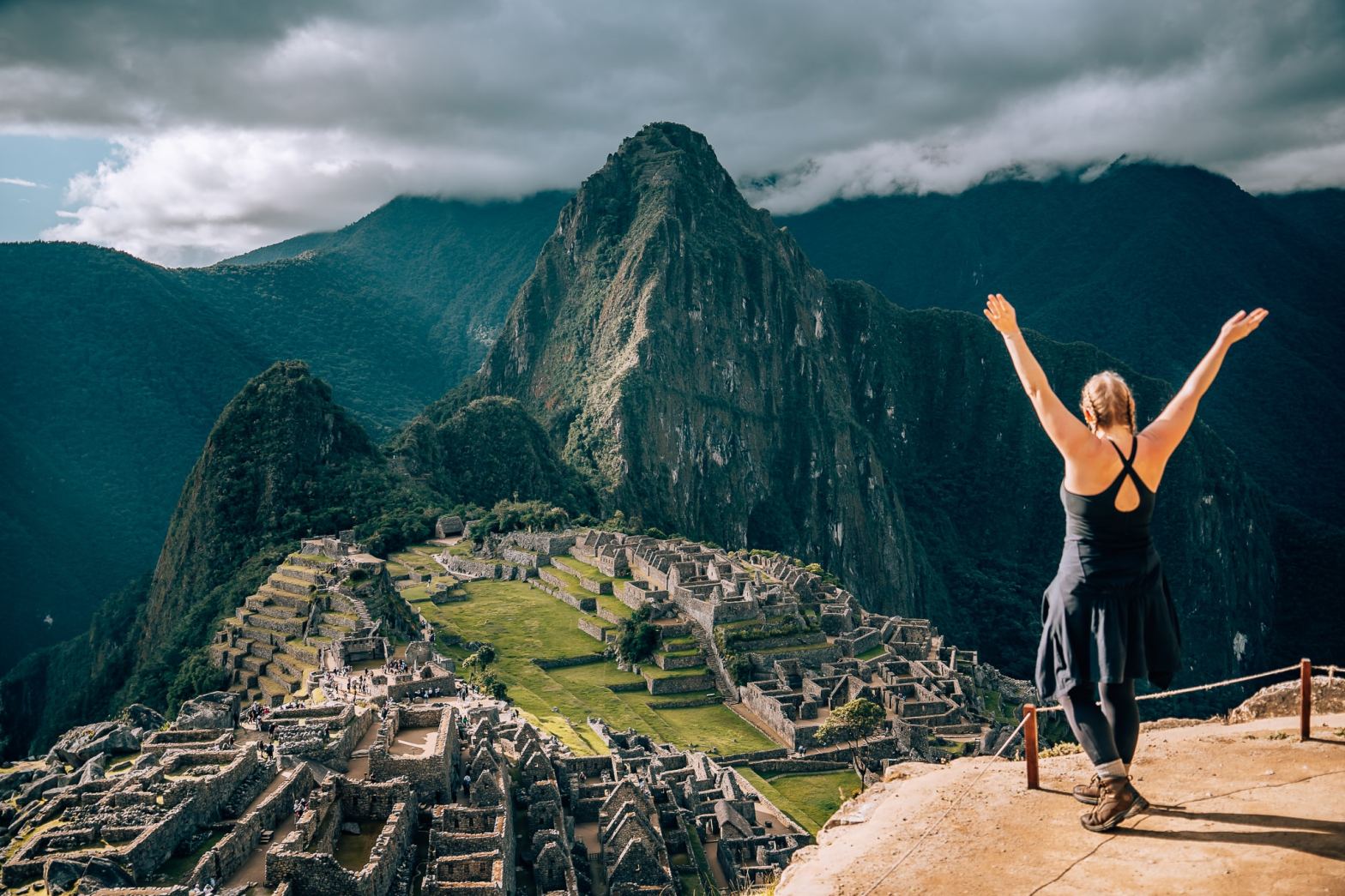 Woman looking out to Machu Picchu Citadel with her arms up