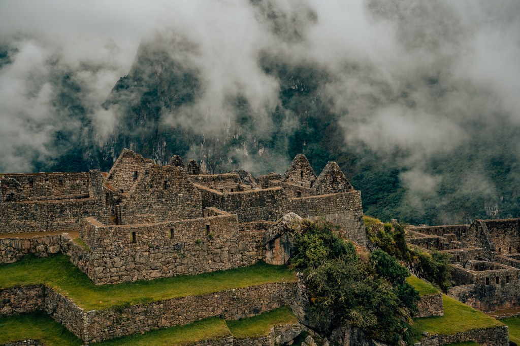 Ruins at Machu Picchu with the mountains covered in clouds in the background