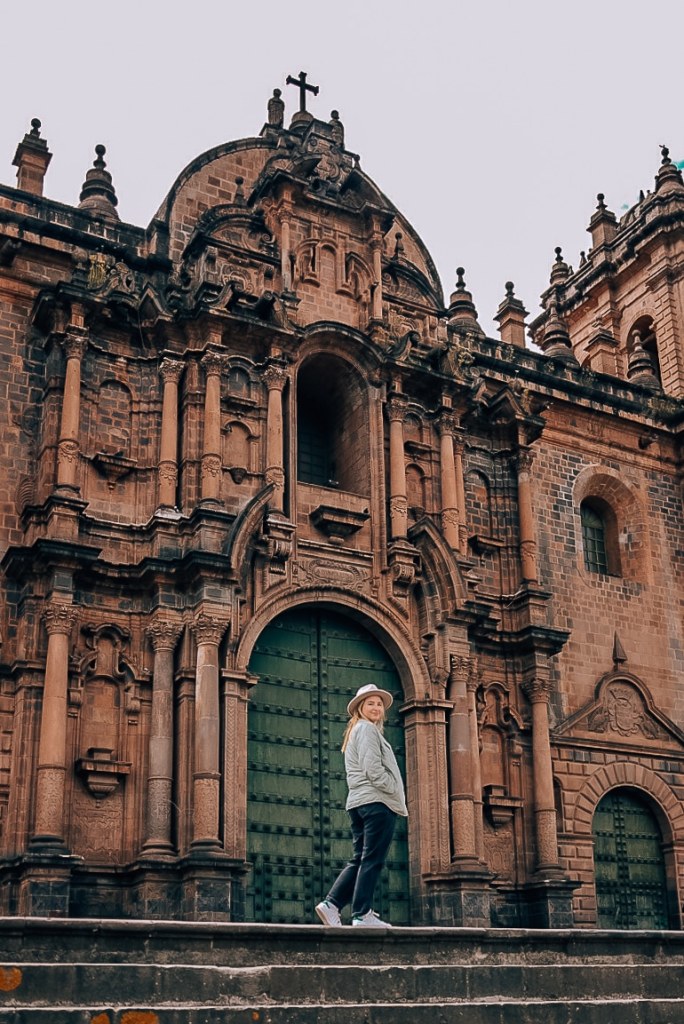 Woman standing in front of a cathedral wearing a hat