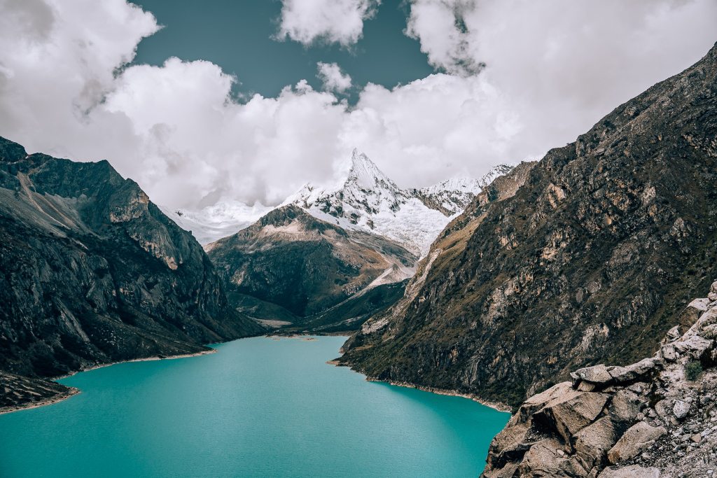 Snow-capped mountain with a bright turquoise alpine lake in front of it
