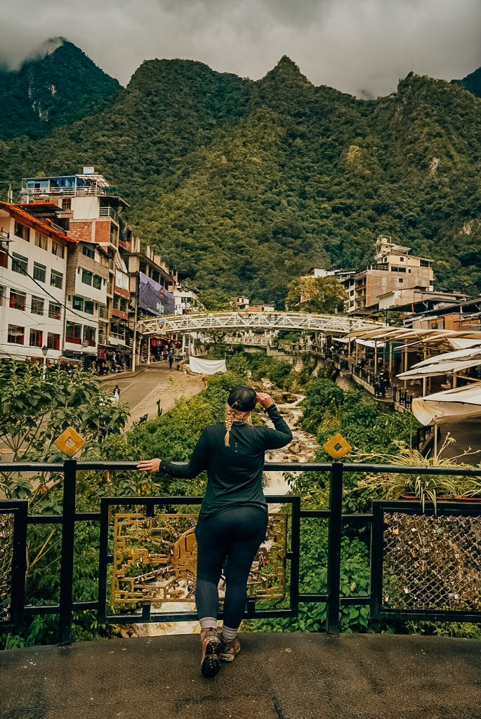 Woman standing on a bridge looking out to the mountains of Aguas Calientes