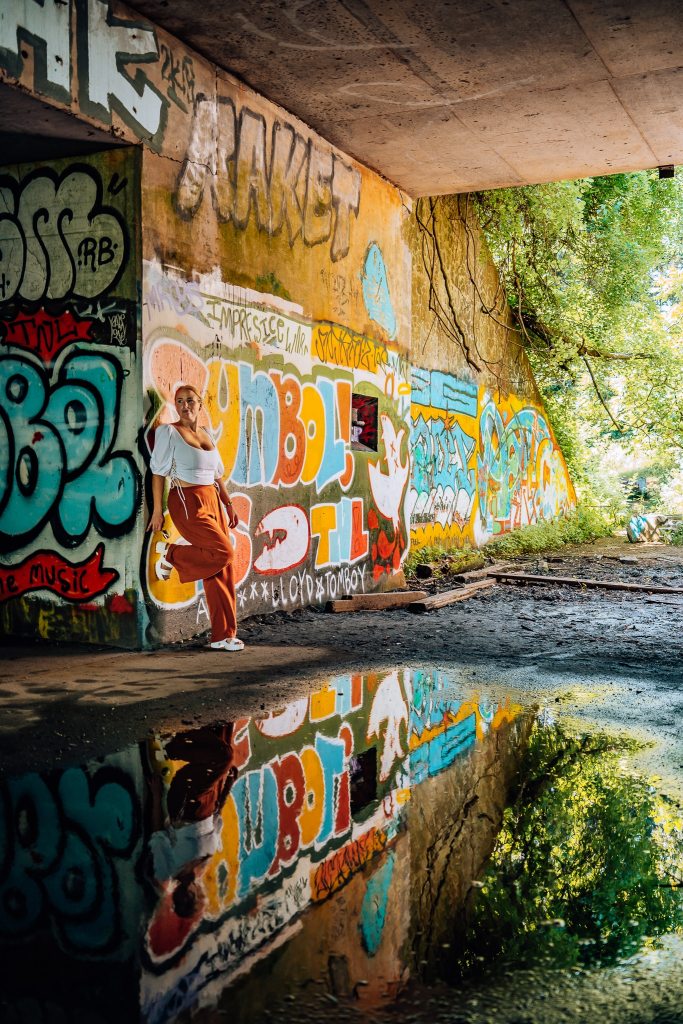 Woman standing in Battery Steele with all the graffiti and a direct reflection below