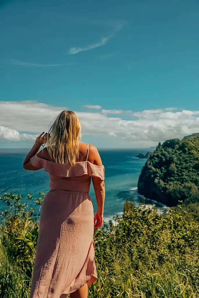 Woman looking out to the Pololu Valley on the Big Island, running her fingers through her hair