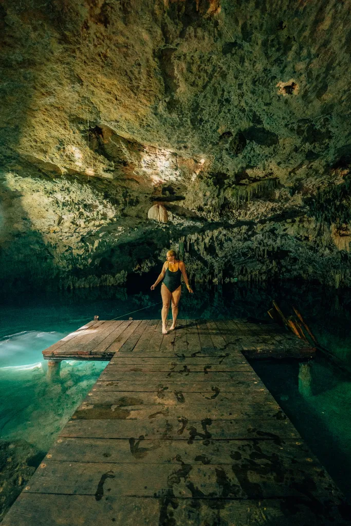 Woman standing at the end of a platform in a cavernous cenote