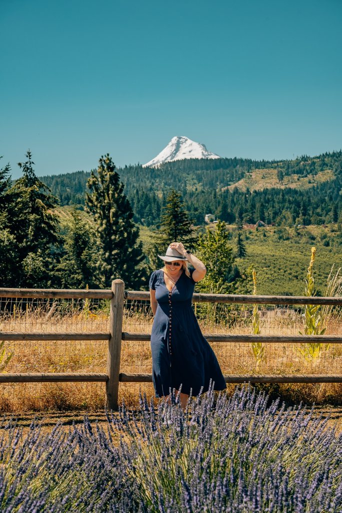Woman in a dress and a hat standing in a lavender farm with Mount Hood in the background