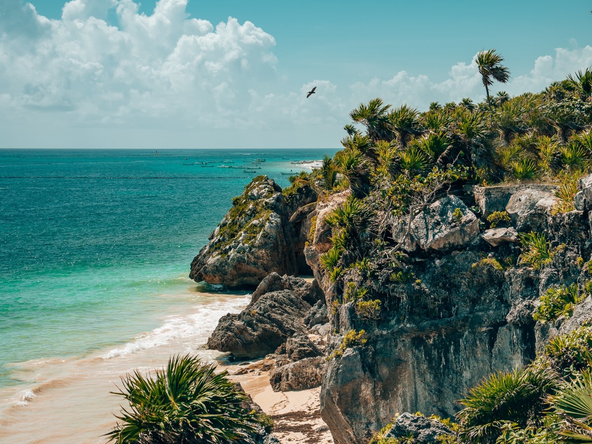 Tulum coastline with rocks and palms leading up to a white beach