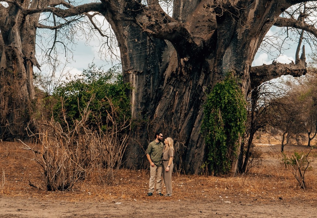 Woman and man standing in front of a large tree on safarh