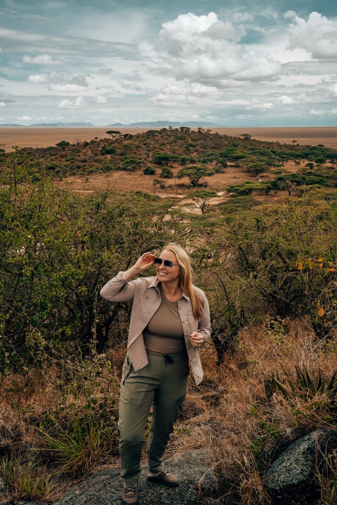 Woman standing on a rock with the Serengeti behind her