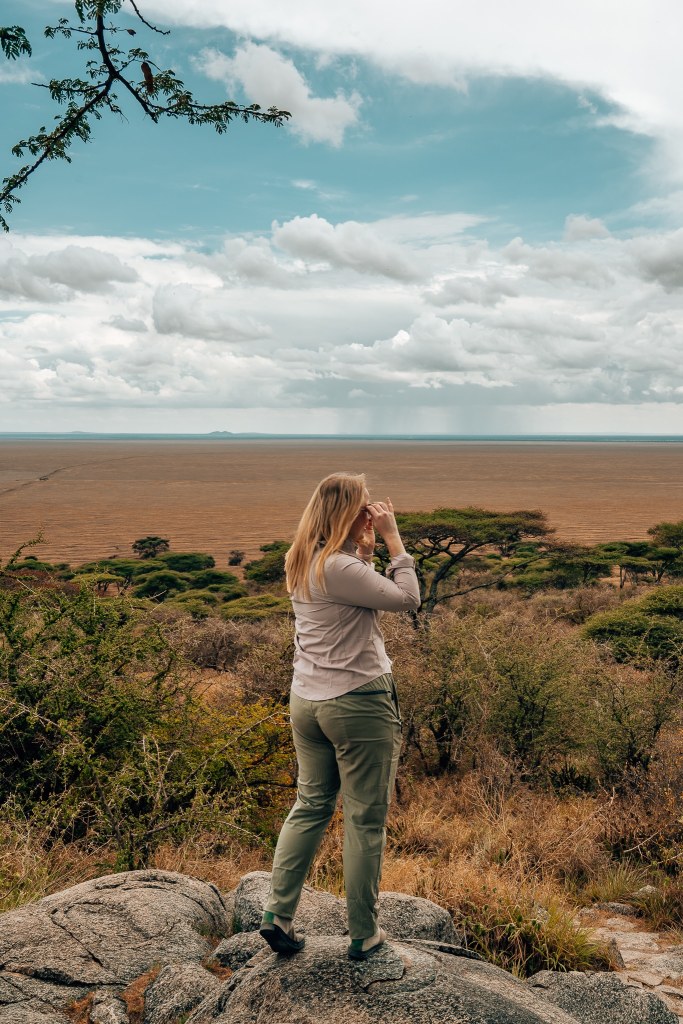 Woman standing on a rock looking out to the Serengeti