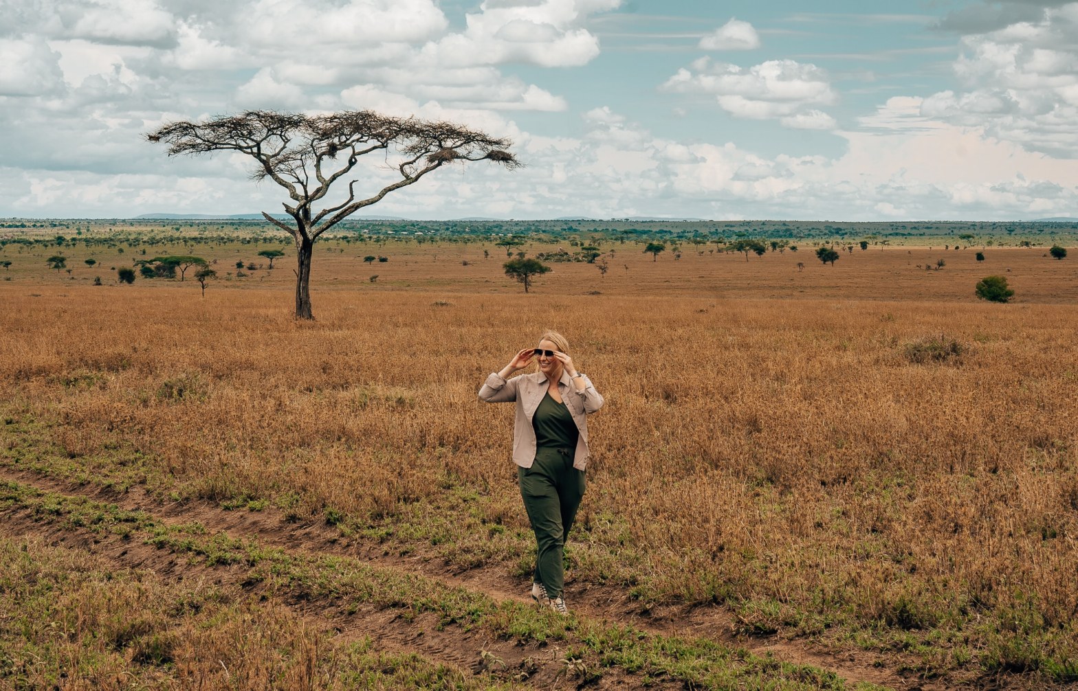 Woman smiling and walking toward the camera while walking through the Serengeti on safari