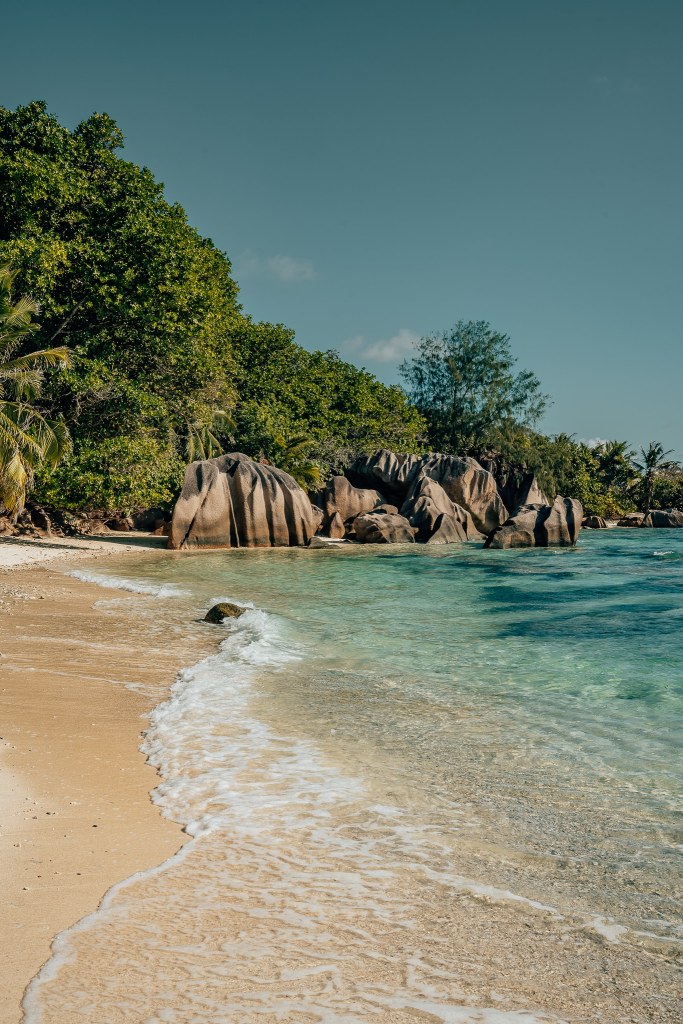 Water on the beach with the granite boulders in the back on La Digue in the Seychelles