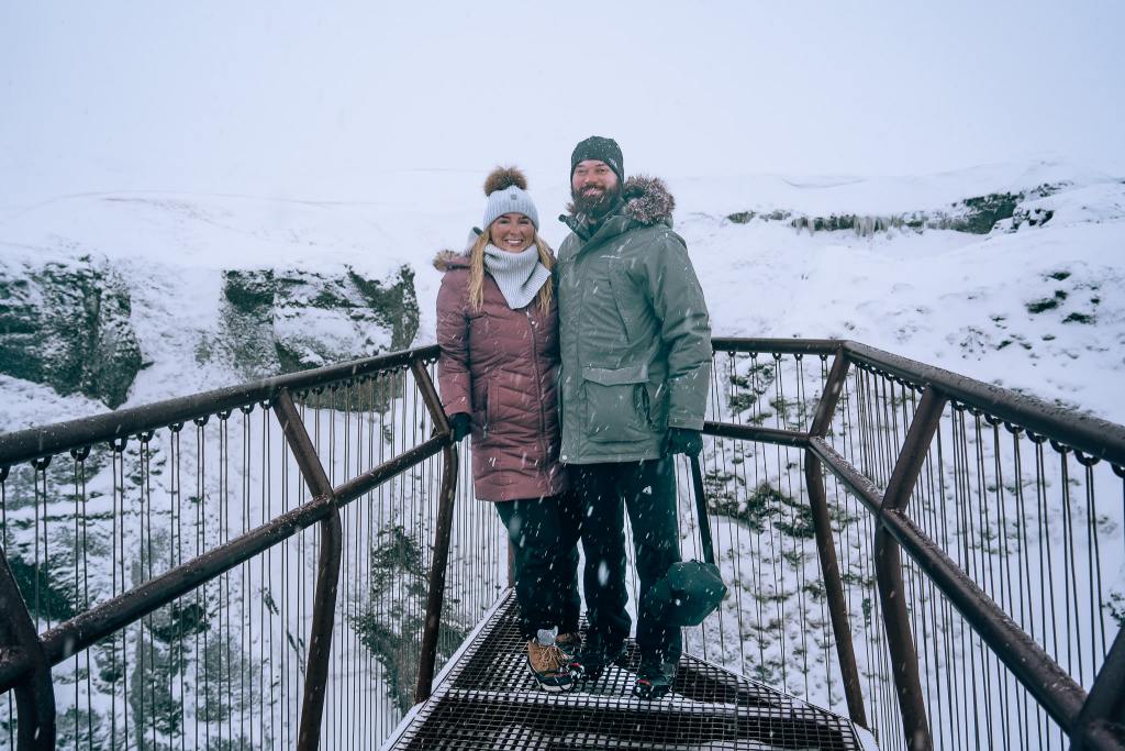 Man and woman standing in the snow in Iceland wearing their full snow outfits