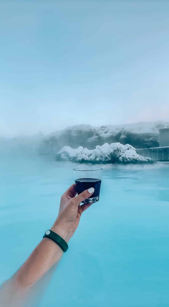 Woman holding a glass of red wine while soaking in the Blue Lagoon