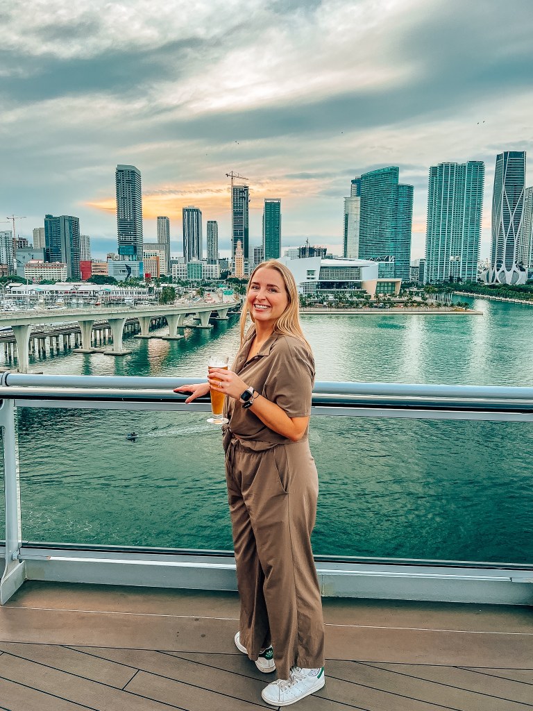 Smiling woman drinking a beer with the Miami skyline at sunset in the background