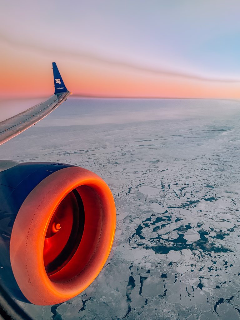 View from the window seat of a flight going over Greenland at sunrise