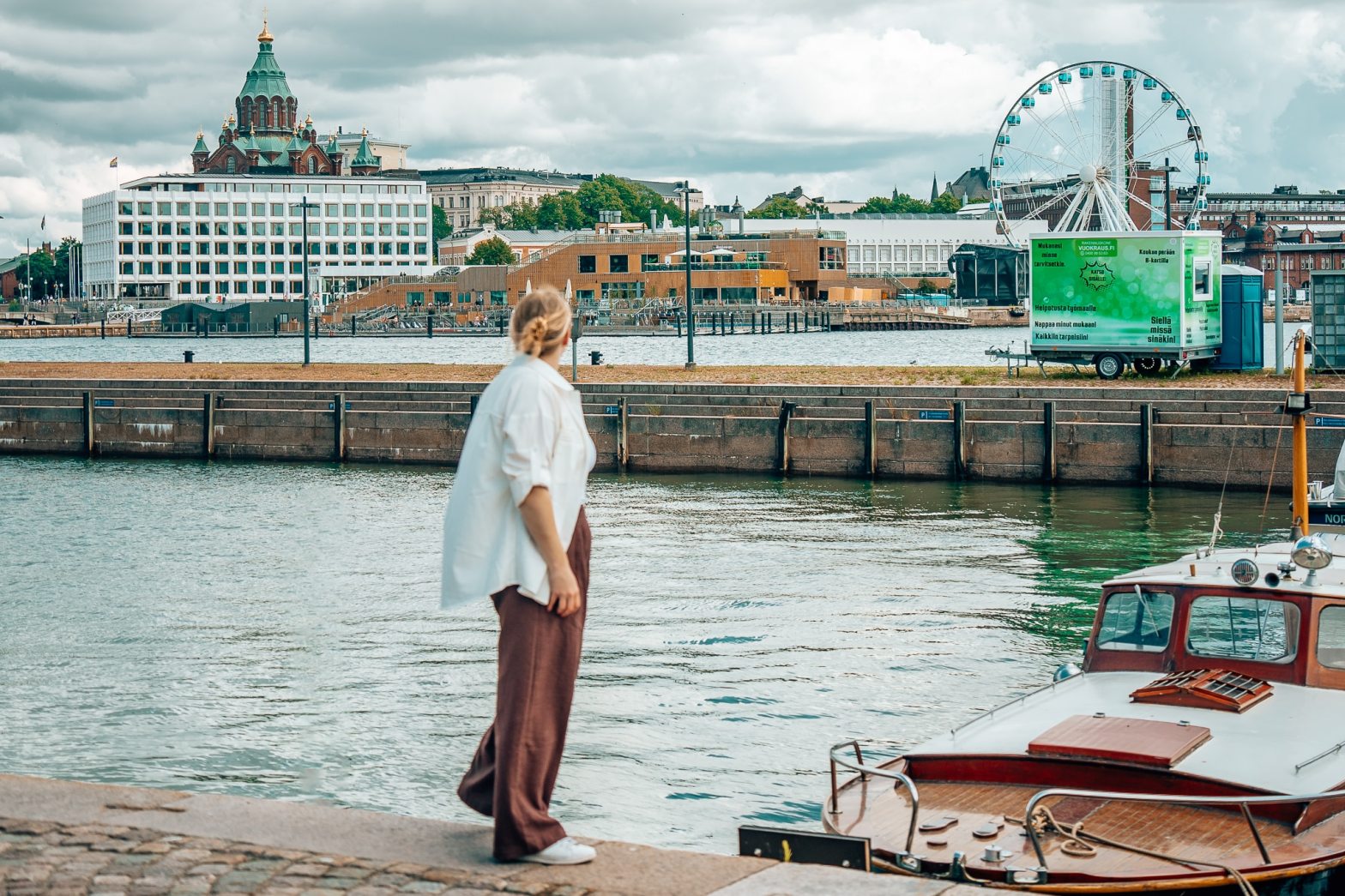 Woman standing in front of a boat with the Helsinki cityscape in the background