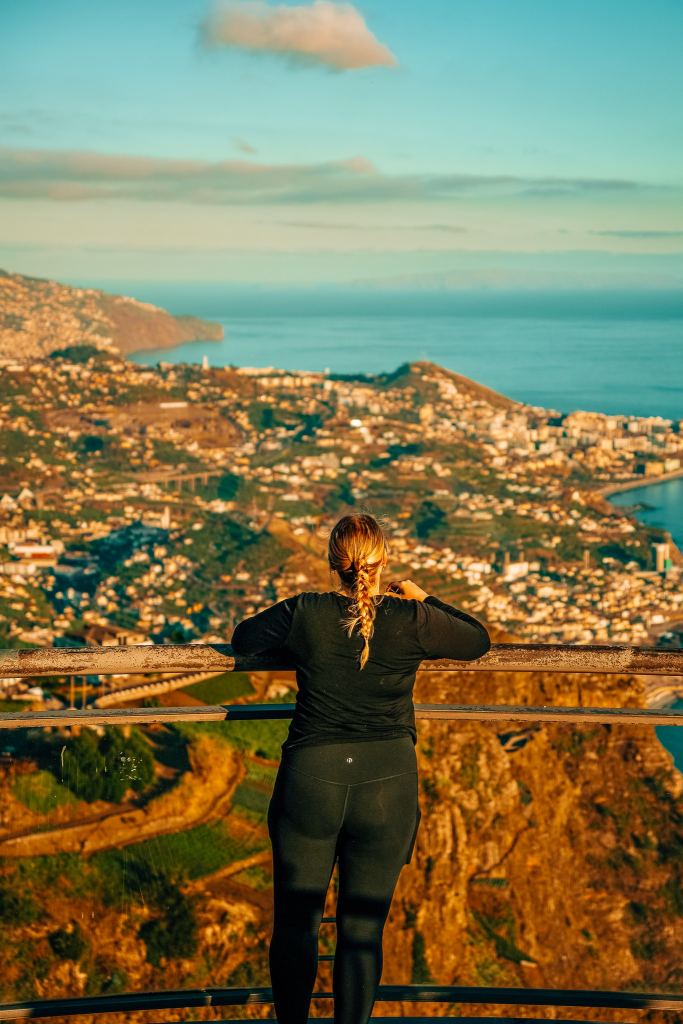 Woman looking out to a town in Madeira at sunset