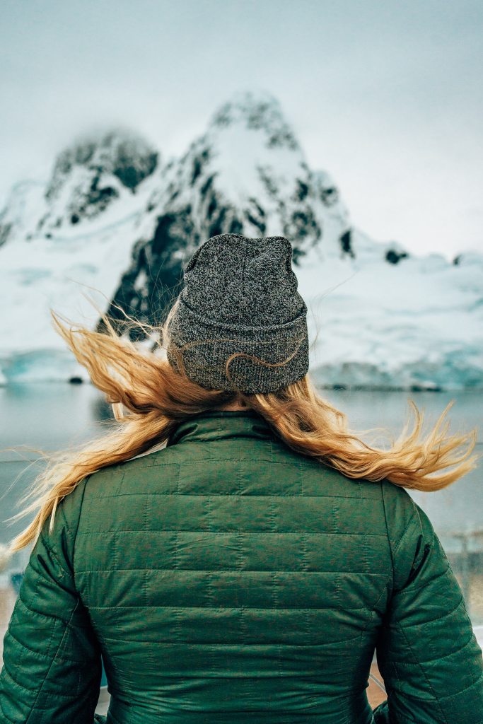 Woman on Antarctic cruise staring out to the mountains with her hair blowing in the wind