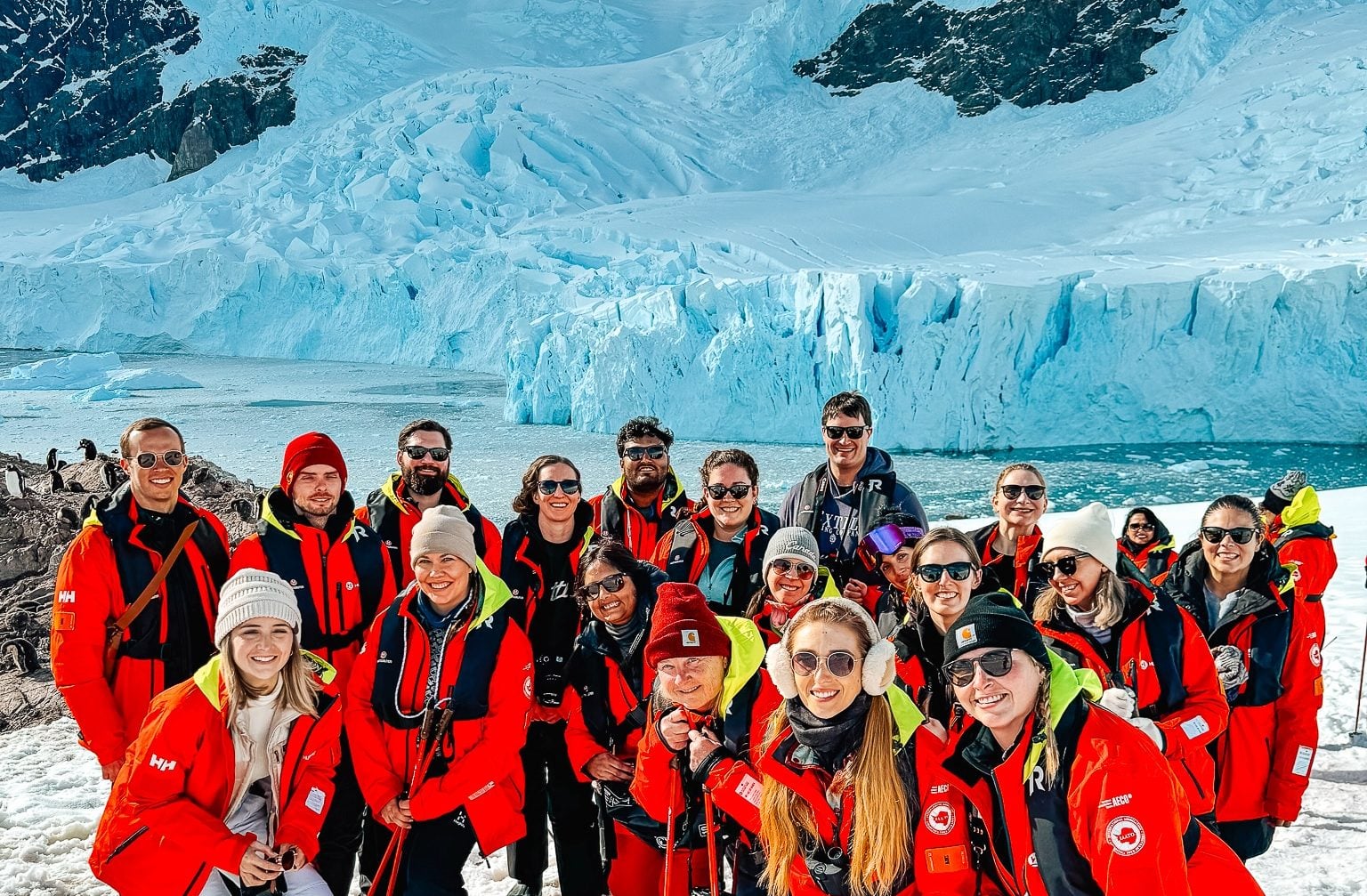 Group of travelers standing in front of a glacier in Antarctica