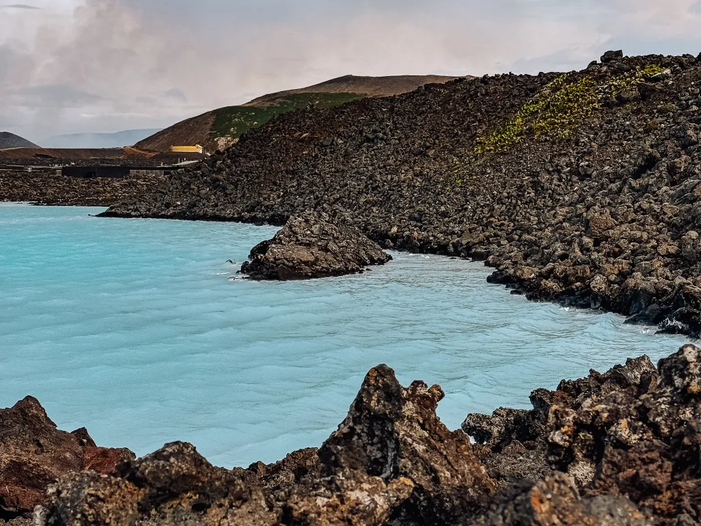 View of the light milky blue water in the Blue Lagoon in Iceland with the black volcanic rocks in the background
