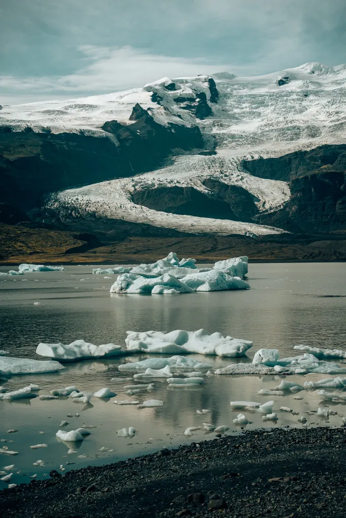 View of Fjallsjokull glacier in Iceland sliding down a mountain and leaving icebergs in a lagoon