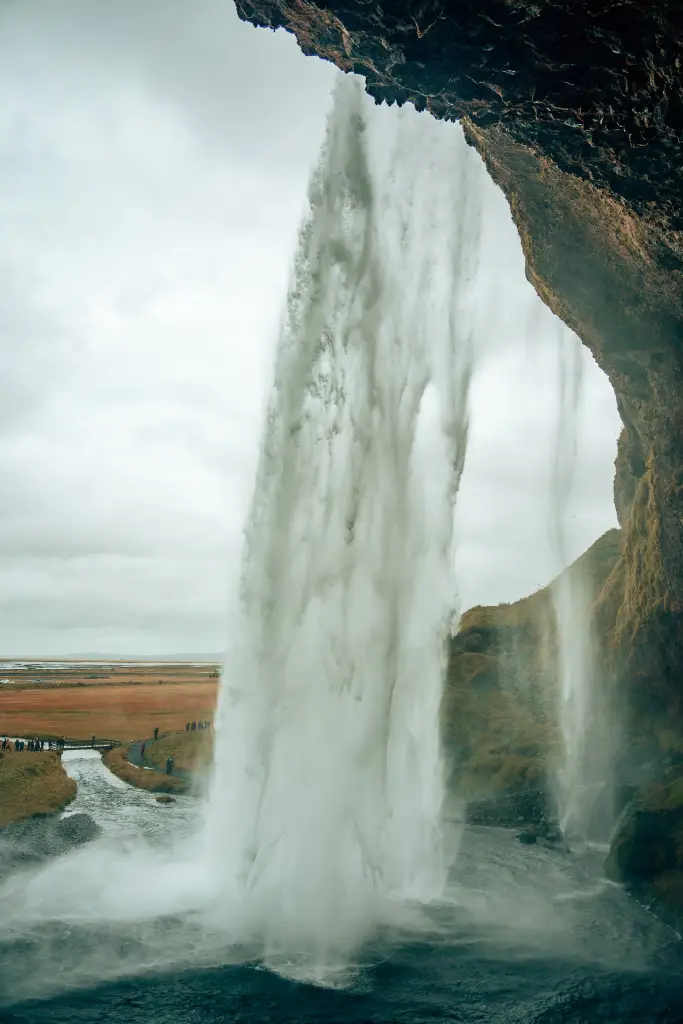View of Iceland's Seljalandsfoss waterfall from behind it with the water flowing over