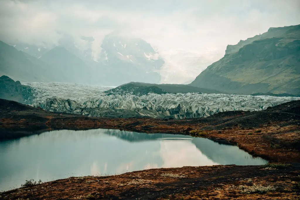 View of Iceland's Svinafellsjökull Glacier with a glacier lake in front, the glacier in the middle, and mountains with the glacier on top