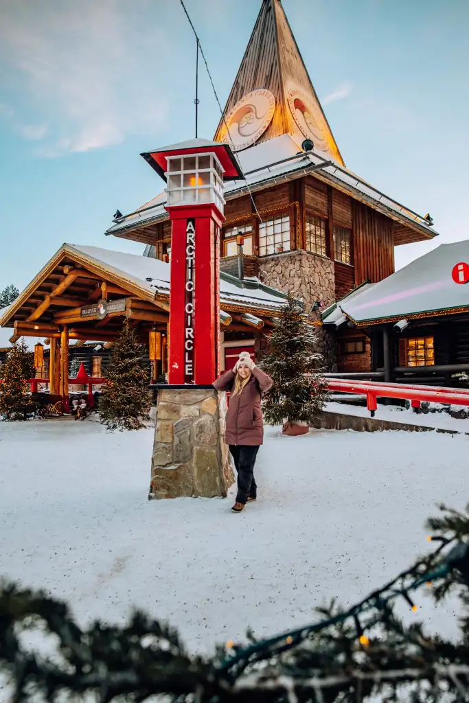 Woman standing next to the Arctic Circle sign in Santa Village in Lapland, Finland