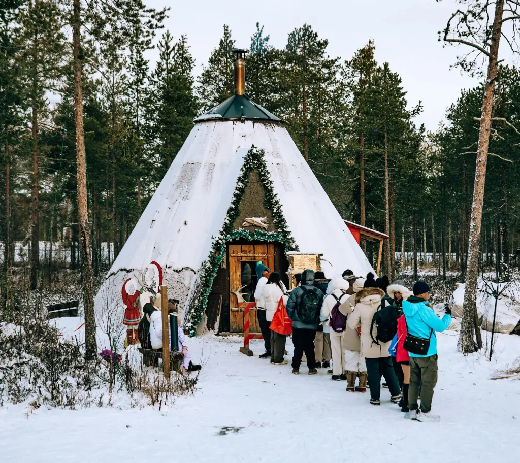 Line of people waiting outside of the Santa's Salmon Place wooden hut at Santa Village in Rovaniemi, Lapland, Finland